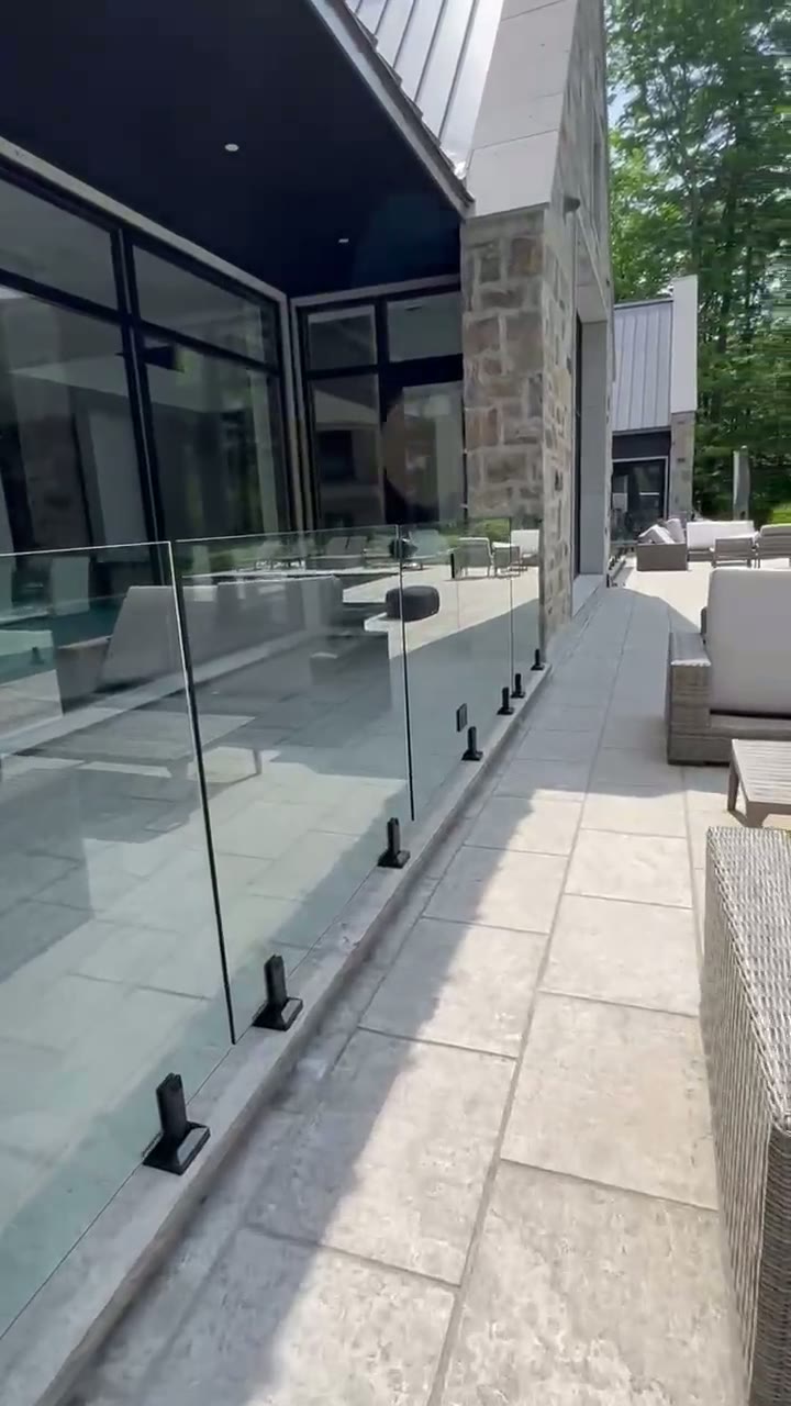 Frameless glass courtyard railing beside a modern stone residence