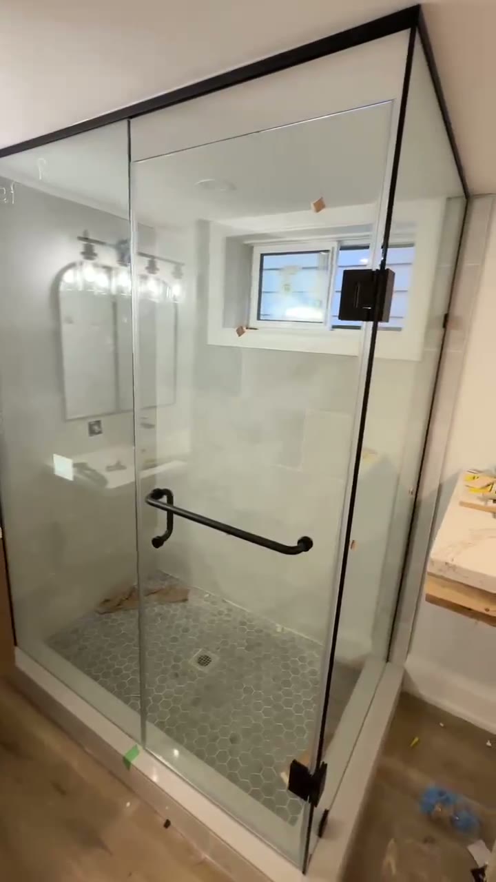 Frameless walk-in glass shower enclosure with black hardware