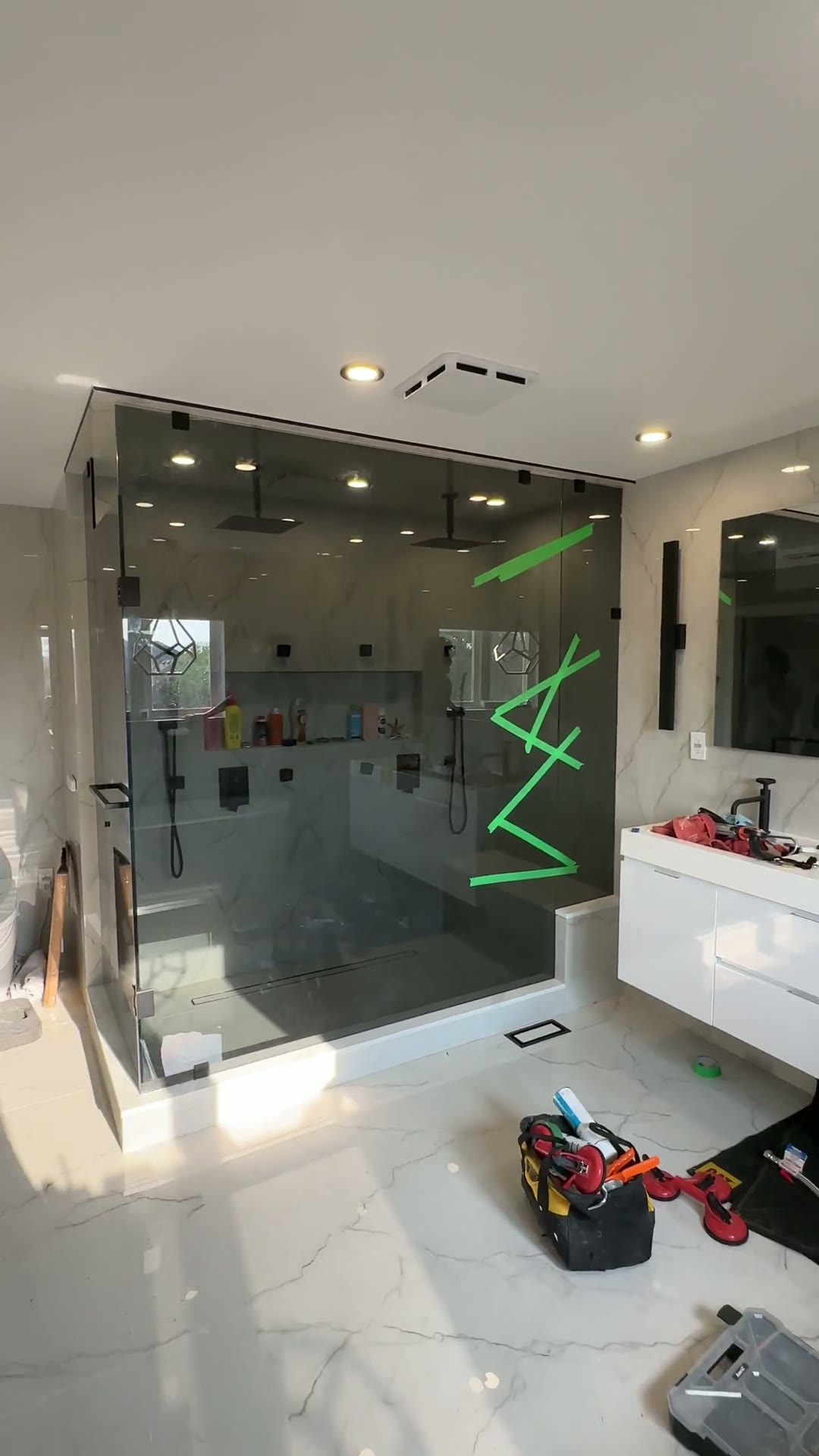 Completed floor-to-ceiling shower enclosure in a bright marble bathroom