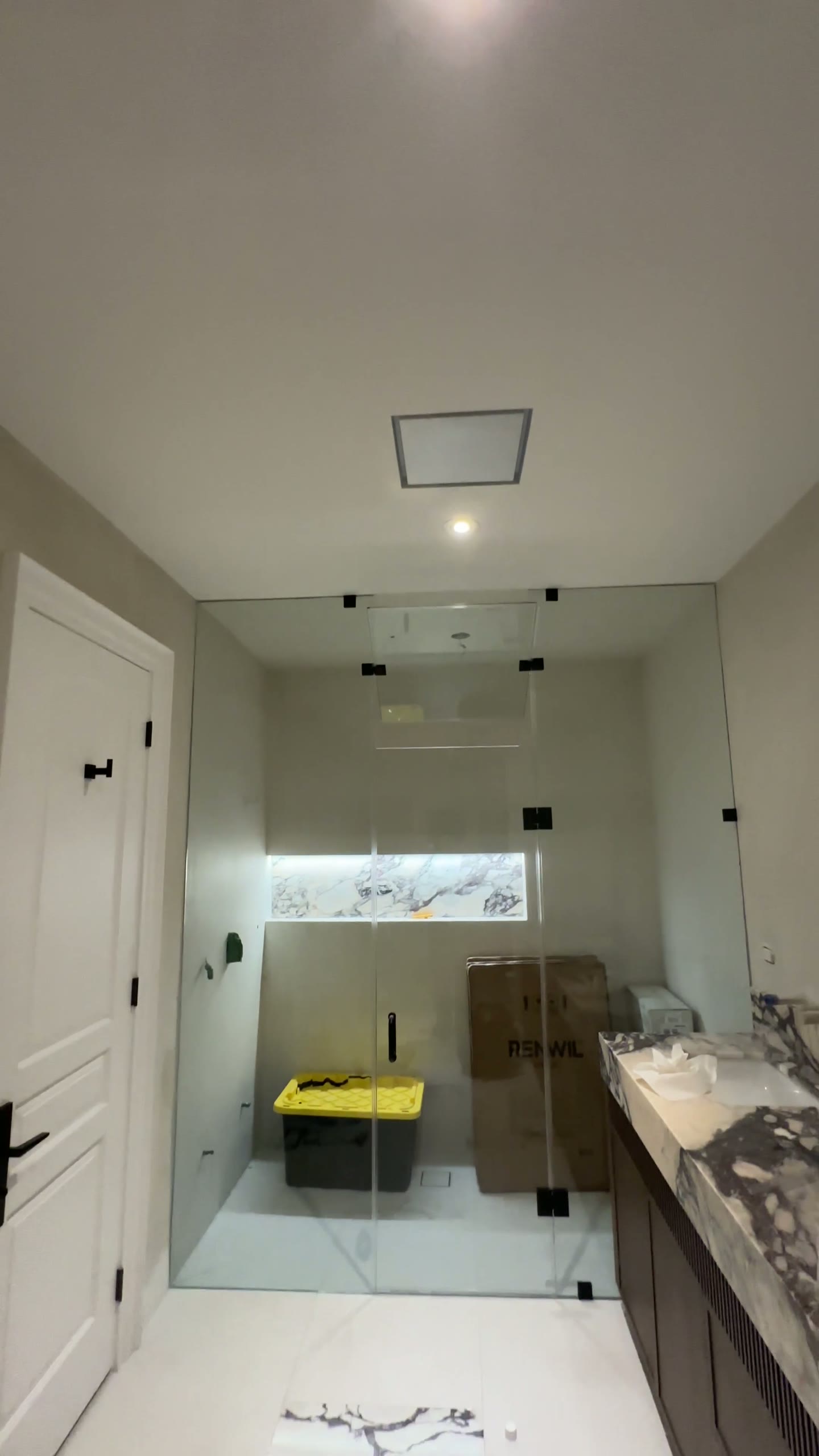 Frameless shower glass with minimal black hardware in a contemporary bathroom