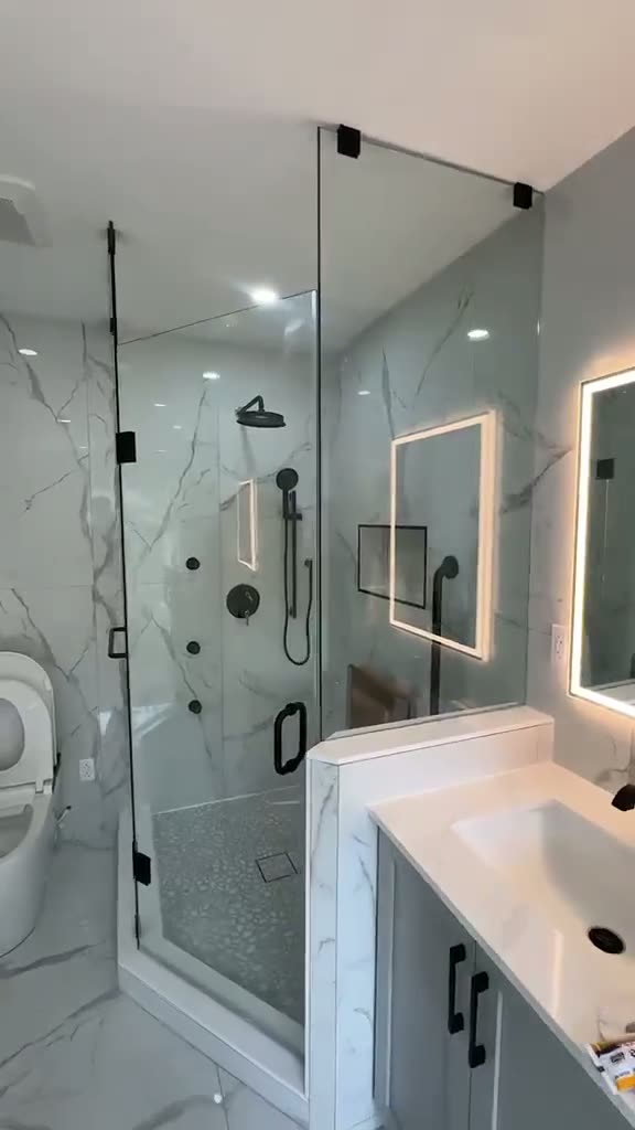 Frameless neo-angle glass shower enclosure in a marble bathroom