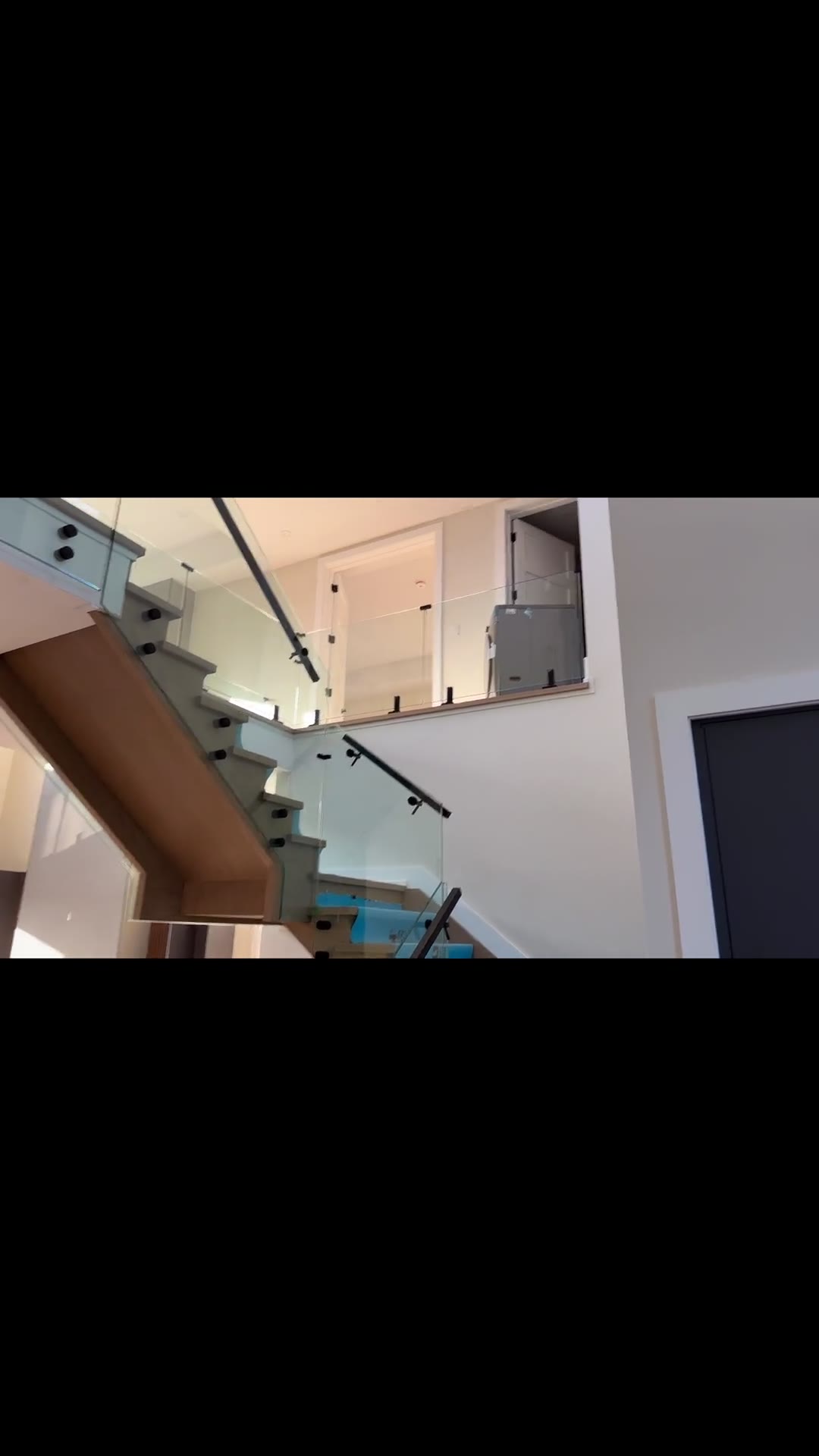 Two-storey custom residence with frameless glass railings around a floating oak staircase