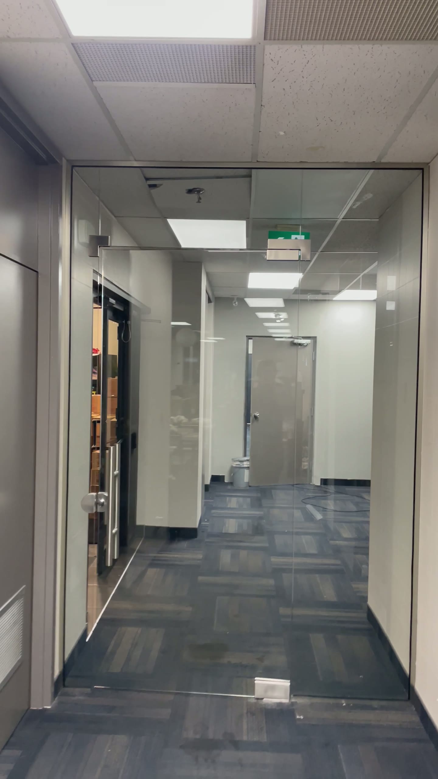 Clear glass office partitions and doors lining a commercial corridor