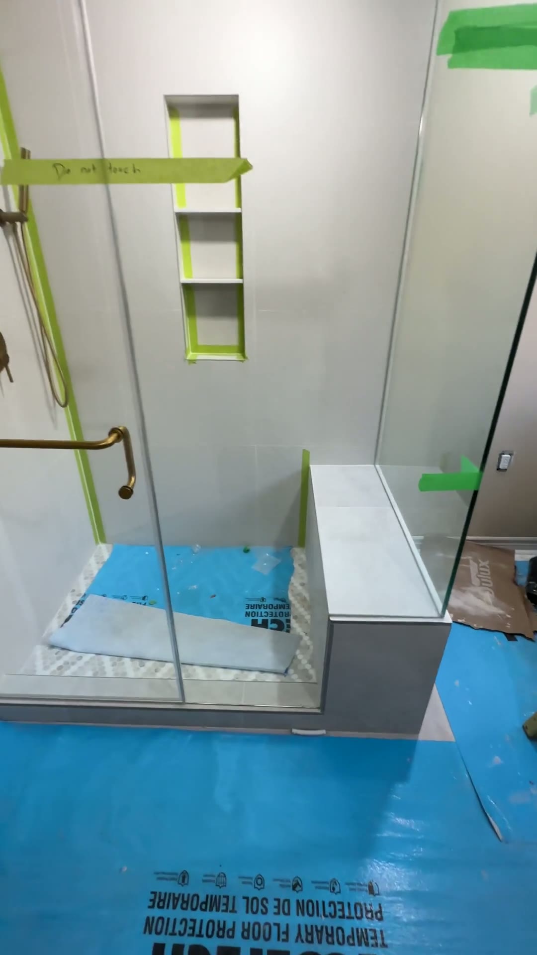 Frameless glass shower enclosure with brushed-brass hardware and built-in bench